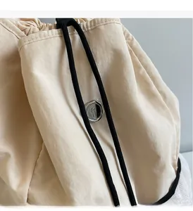 Detail of nylon canvas backpack showing the silver logo buckle and black drawstring