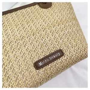 Close-up of handwoven straw bag featuring brown leather trim and Micro beauty logo