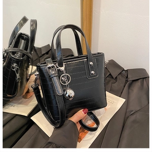 Détail du sac seau en cuir embossé noir avec breloque boule argentée et double poignées