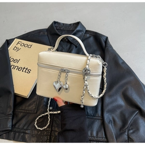 Détail du sac seau blanc texture crocodile avec pendentif cœur et bandoulière chaîne