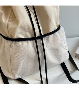 Detail view of cream nylon backpack fabric with white mesh side pocket and drawstring closure