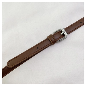 Detailed close-up of dark brown leather strap with silver buckle and refined stitching