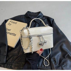 Détail du sac boîte blanc gaufré avec breloque en cœur et bandoulière en chaîne