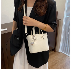 Détail du sac seau crème avec breloque boule argentée et bandoulière texturée