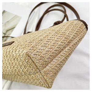 Close-up of straw woven bag with premium brown leather trim and cross-weave texture