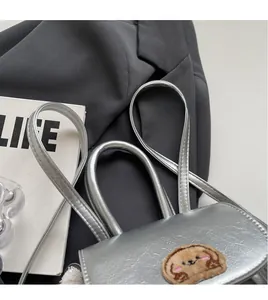Dettaglio macro della mini borsa argento con ricamo a cane e tracolla lunga e sottile