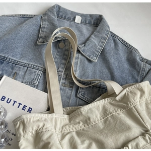 Detail van geplooide shopper met geweven riem op denim met zichtbare stiksels