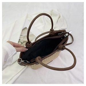 Detail of hand-woven straw tote bag showing brown leather handles and inner zipper pocket
