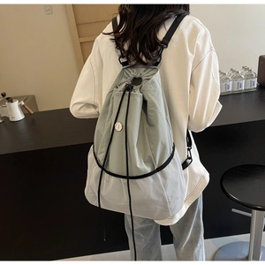 Detail of light green nylon drawstring backpack with breathable white mesh and metal badge