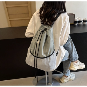 Detail of grey-blue nylon drawstring backpack featuring breathable mesh and metal logo