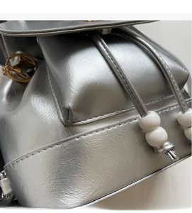 Dettaglio dello zaino metallico argento con coulisse e trama in morbida pelle PU