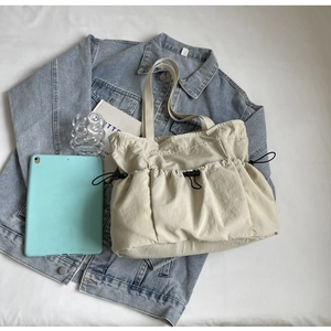 Detail van beige geplooide shopper met grote zijvakken en trekkoord sluiting