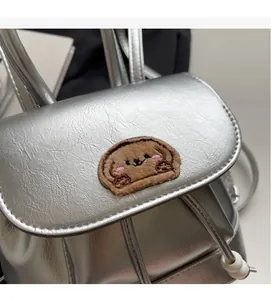 Dettaglio mini zaino argento con toppa orsetto di peluche e coulisse con perline