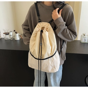 Detail of beige nylon drawstring backpack with white mesh bottom in a cafe setting