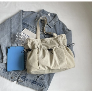 Detail van beige geplooide nylon tote bag met handige zakken en een trekkoord sluiting