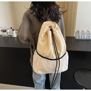 Close-up of beige nylon drawstring backpack featuring a white mesh front pocket