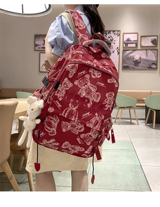 Detail eines roten Rucksacks mit Bären-Graffiti, MDBAG-Stickerei und Hasen-Anhänger