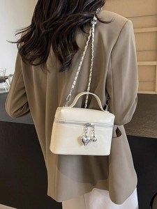 Sac bandoulière beige chic avec pendentif cœur et bandoulière chaîne sur modèle