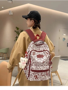 Detailansicht weißer Graffiti-Rucksack mit roten Riemen und Plüschbär-Anhänger