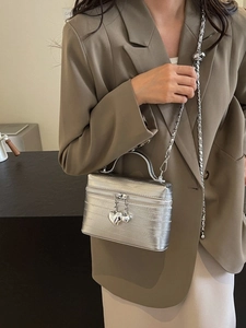Sac à main boîte argenté métallisé avec breloques cœur et bandoulière chaîne sur modèle