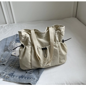 Detail van beige nylon shopper met trekkoordsluiting en geweven handvatten