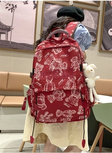 Roter Rucksack mit weißen Bärenmustern und Plüschhasen-Anhänger am Modell