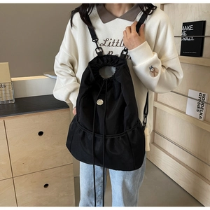 Detail of black nylon drawstring backpack featuring a unique bottom mesh pocket and metal buckle