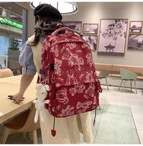 Detail eines roten Rucksacks mit Bärenprint, MDBAG-Stickerei und weißem Hasenanhänger