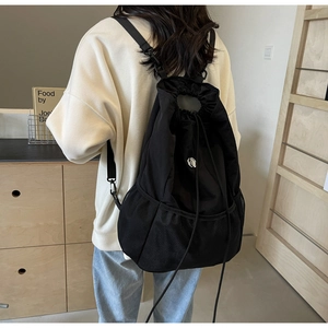 Detail of black nylon drawstring backpack featuring mesh pockets and round handle grip
