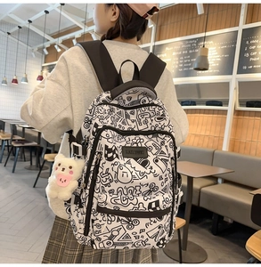 Detailansicht eines Schülerrucksacks mit Cartoon-Graffiti und Plüschbär-Anhänger