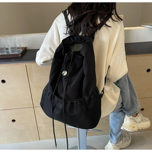 Detail of black nylon drawstring backpack with mesh pocket shown on female model