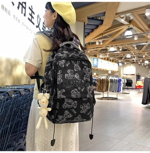 Detail eines schwarzen Rucksacks mit Bärenmuster, MDBAG-Schriftzug und Hasenanhänger