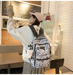 Graffiti-Rucksack aus Canvas mit Bärenanhänger am Modell in gemütlicher Cafè-Umgebung