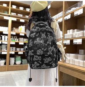 Detail eines schwarzen Rucksacks mit Bärenmuster und Plüschhasen-Anhänger im Geschäft