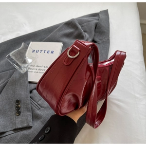 Détail du sac à bandoulière bordeaux motif crocodile avec boucles en métal argenté