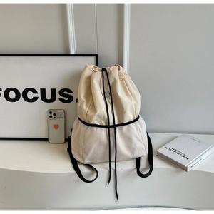 Detail of beige nylon backpack featuring white mesh panel and black drawstring closure