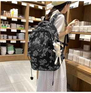 Detail eines schwarzen Rucksacks mit Bärenprints, MOBAG-Stickerei und Hasenanhänger