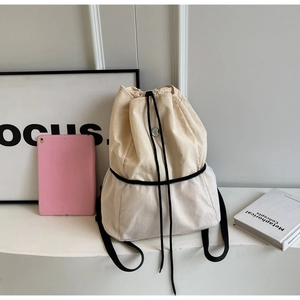 Detail view of beige canvas drawstring bag with white mesh panel and silver metal buckle