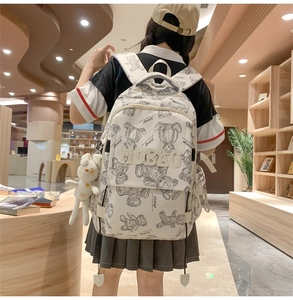 Detail eines weißen Rucksacks mit Bärenmuster und Hasenanhänger in einer Bibliothek