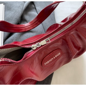 Détail du sac plissé bordeaux brillant avec zip argenté et étiquette fashion