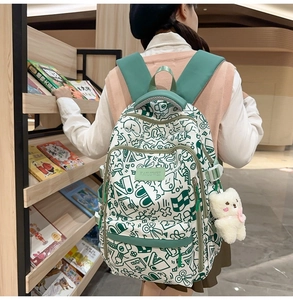 Nahaufnahme des Graffiti-Rucksacks mit weißem Bärenanhänger und grünen Gurten