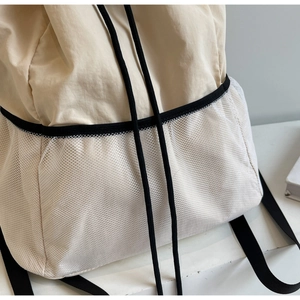 Close-up of beige nylon backpack with side honeycomb mesh pocket and drawstring details
