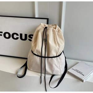 Detail of drawstring canvas backpack featuring beige fabric and white mesh panel design
