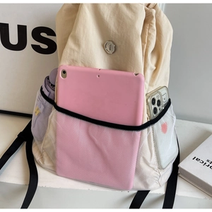 Detail of beige nylon backpack showing spacious mesh pocket with tablet and accessories