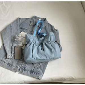 Detail van lichtblauwe stoffen shopper met trekkoordtextuur en bijpassende riem