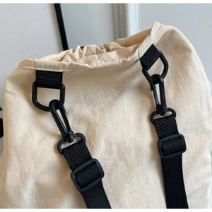 Detail of durable black D-ring and buckle hardware on cream nylon backpack strap