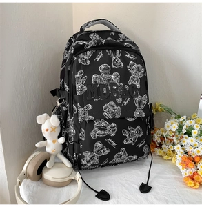 Nahaufnahme vom schwarzen Schulrucksack mit Bärenprint und weißem Plüschhasen-Anhänger