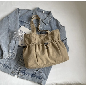 Minimalistische khakifarbene Crossbody-Tasche aus gewaschenem Stoff auf blauem Denim-Hintergrund