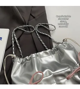 Detail of silver metallic drawstring bag with woven chain strap and pink decorative cords