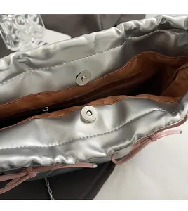 Detail view of silver metallic bag with brown fabric lining and magnetic closure